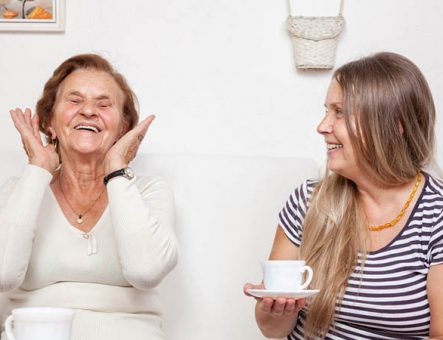 A carer having a chat over a cup of tea with an elderly woman.