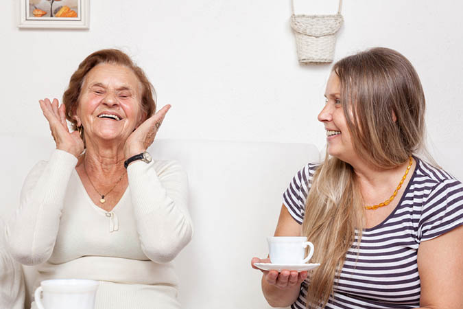 A carer having a chat over a cup of tea with an elderly woman.