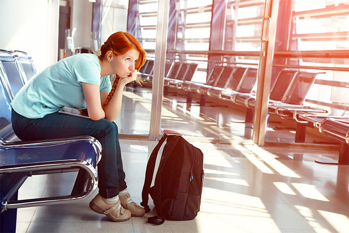 A woman waits bored at an airport after her flight is delayed