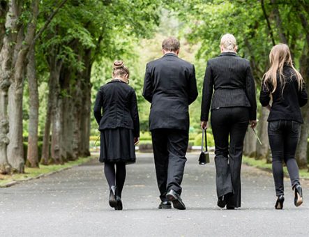 A group walk away from a funeral, dressed in black.