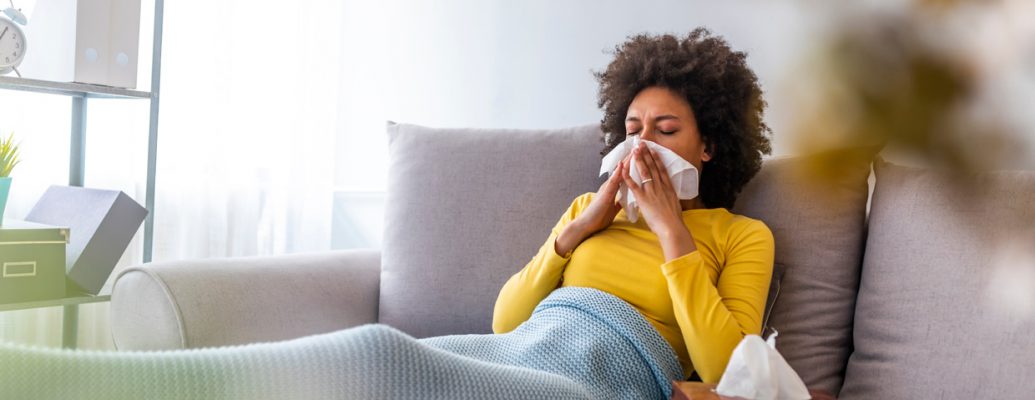 Woman feeling unwell at home with blanket and tissues