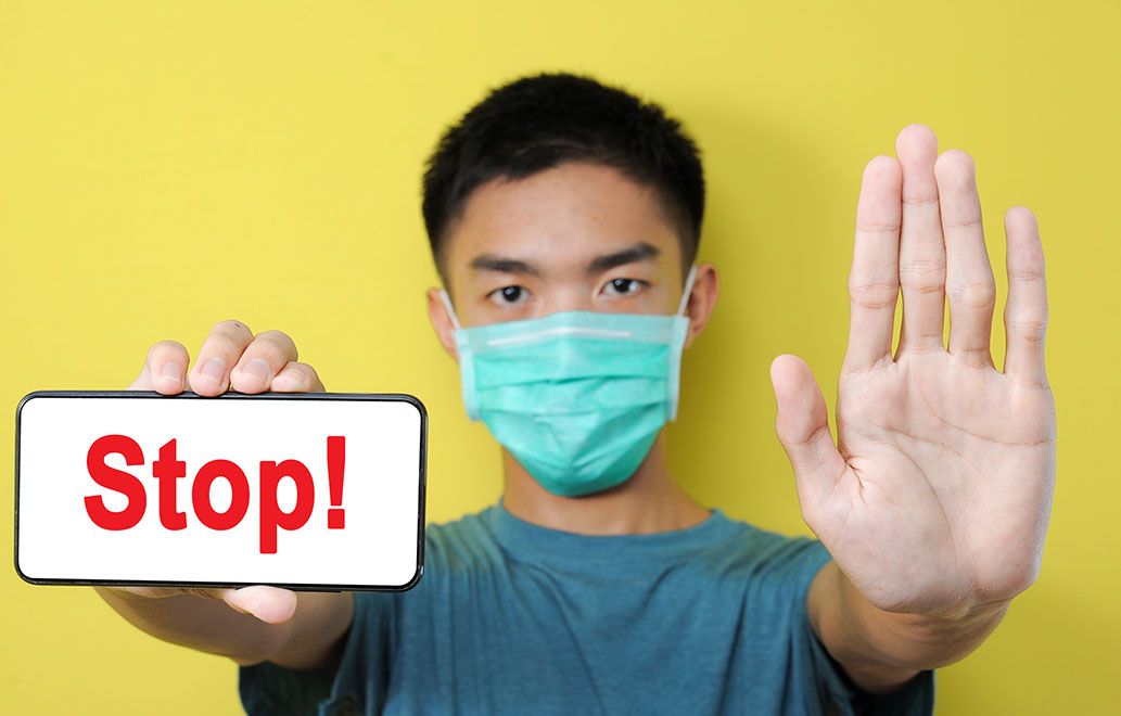 a man with a face mask holding a sign saying stop