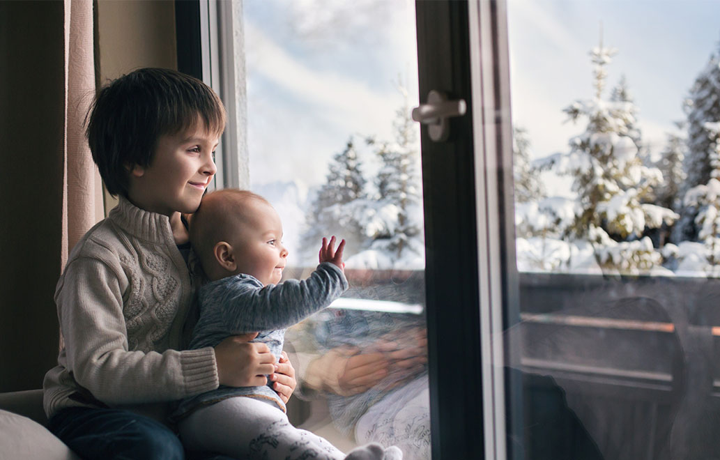 a child with younger sibling looking out of window