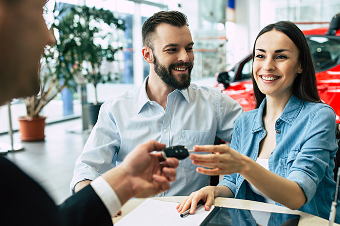 a couple being handed keys to a new car