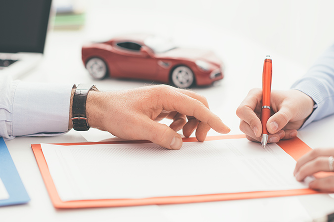 a close up of someone signing a car loan agreement
