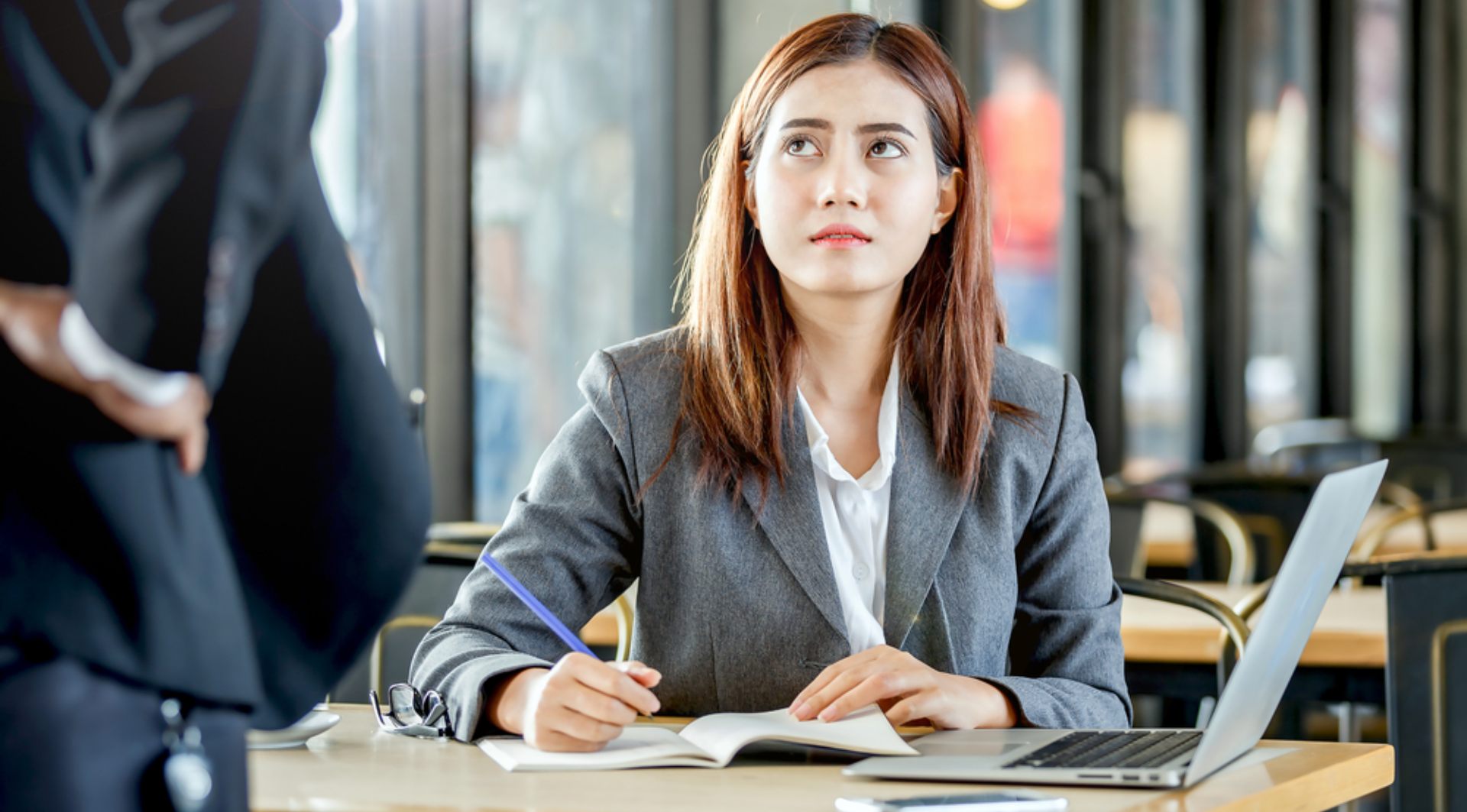 A girl sitting at a desk looking intimidated by a man