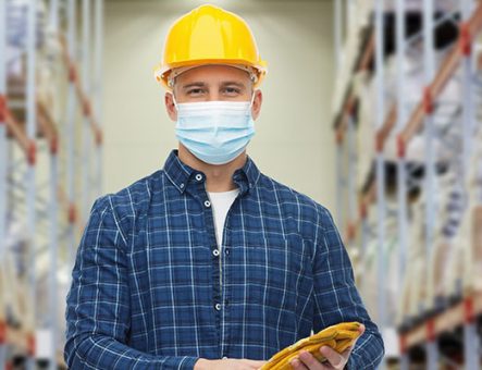 Employee wearing a facemask and yellow hard hat at work