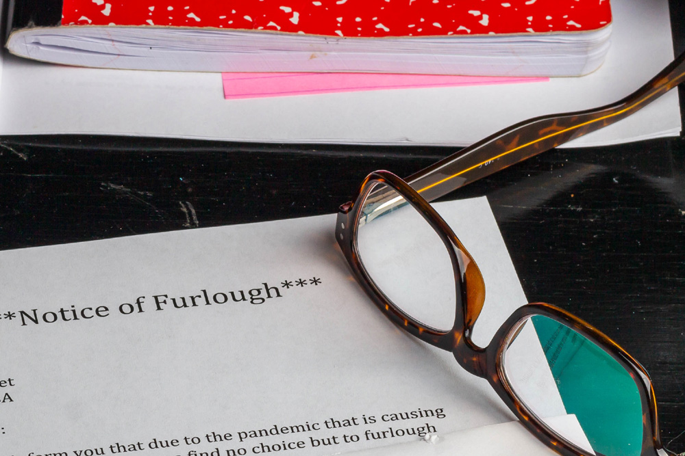 Notice of Furlough letter on desk with pair of glasses and notebooks