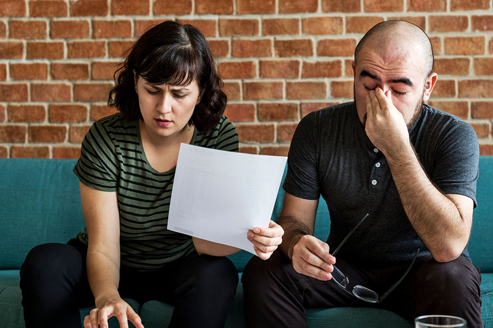 A man and woman worry and stress over bills and invoices.