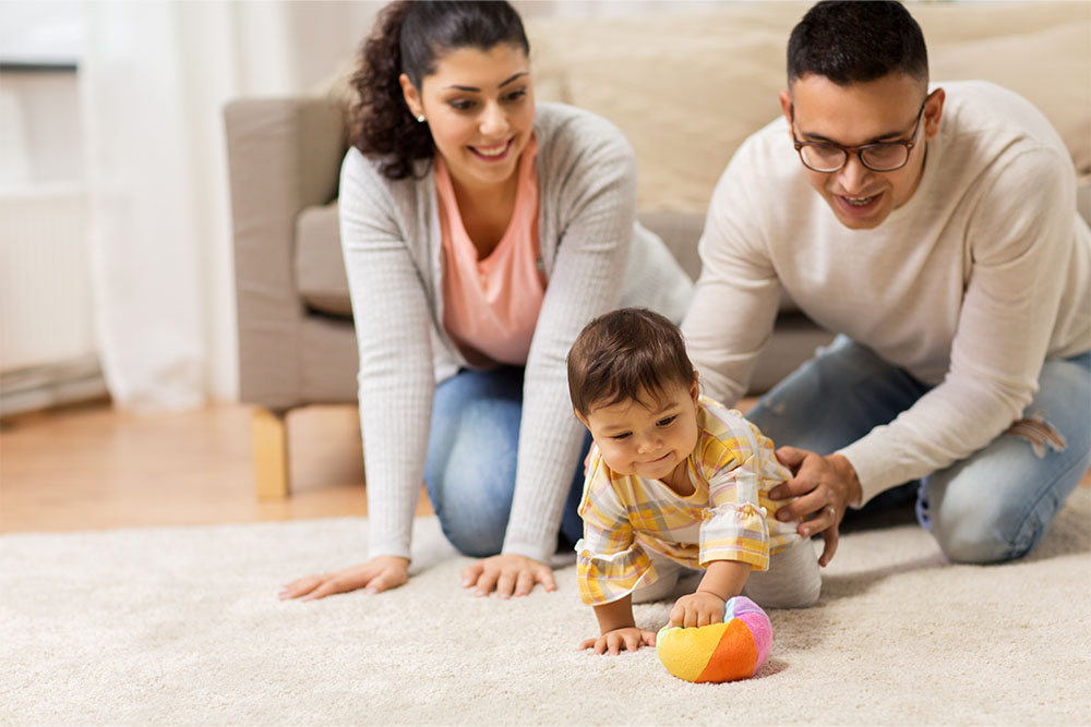 Mum and dad play with child on the floor