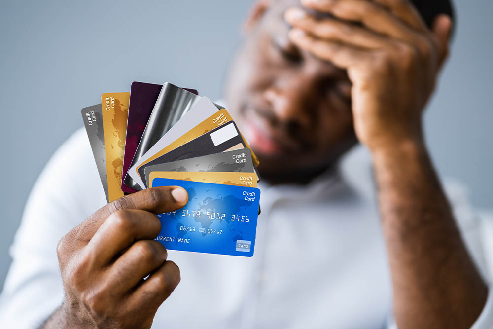 A man looks despairingly at his credit cards which are fanned out in front of his face
