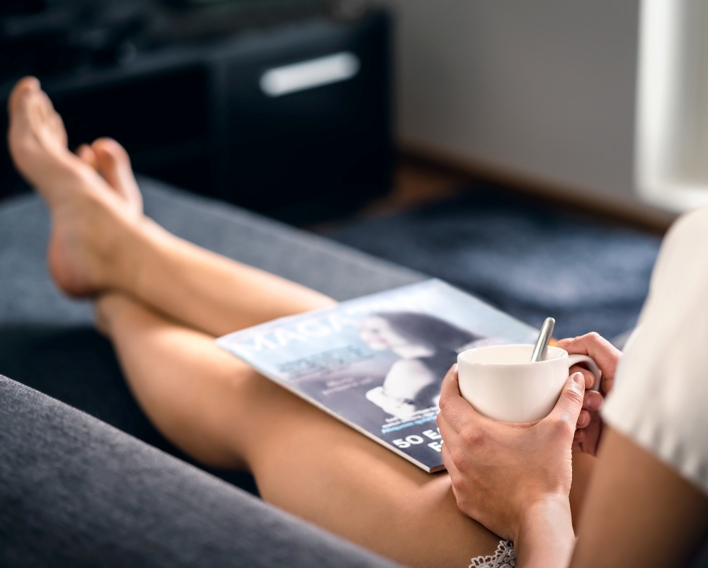 Woman relaxing on a sofa with a coffee and a magazine