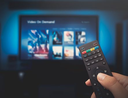 A remote control in front of a TV subscription service.