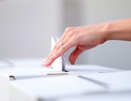 Famle hand posting vote into a ballot box