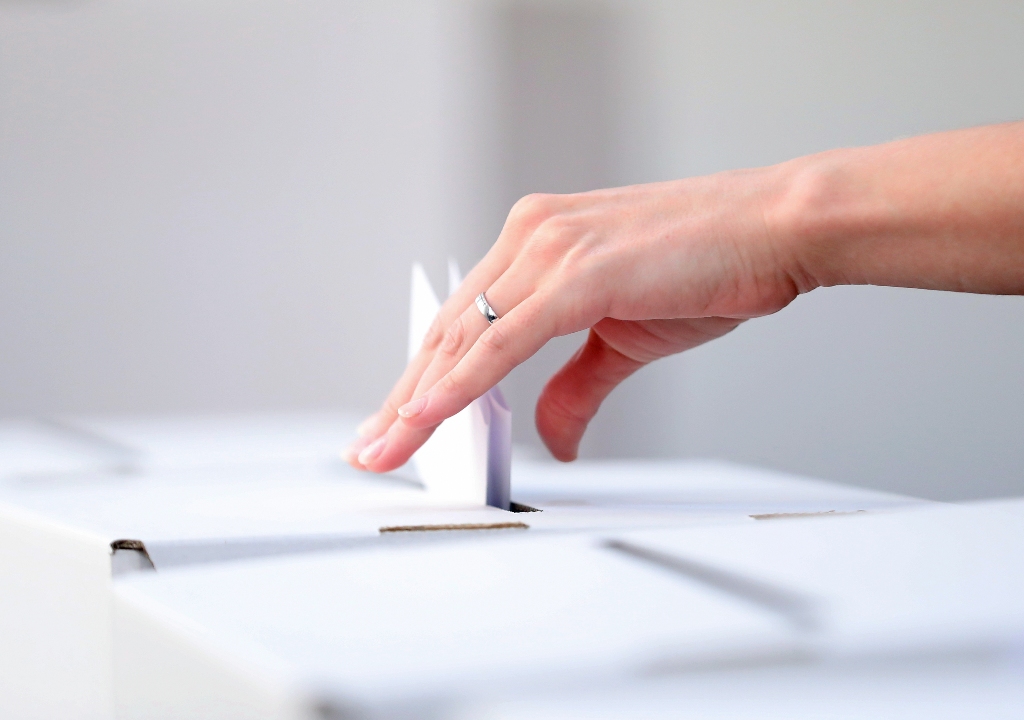 Famle hand posting vote into a ballot box