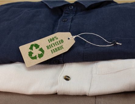 Clothes made from recycled fabric folded on wooden bench