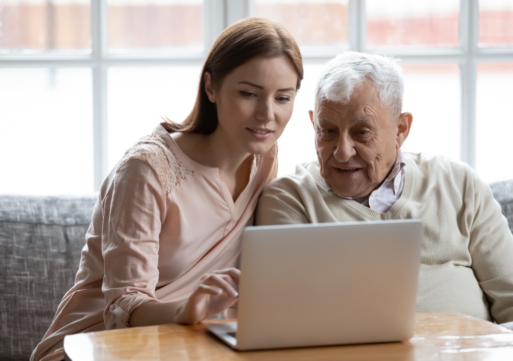 Young woamn showing older man hw to use a computer