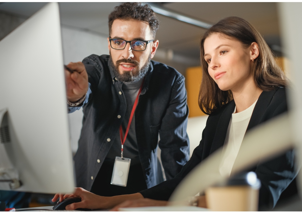 Photo of a man helping a woman at a laptop