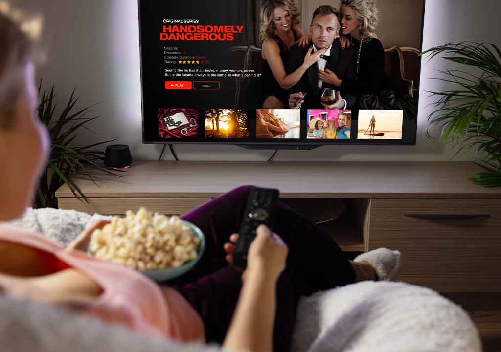 A lady holding popcord and watching Netflix. 