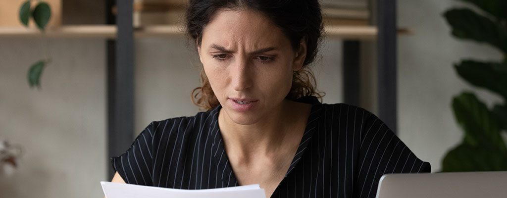 A worried woman looking at paper.