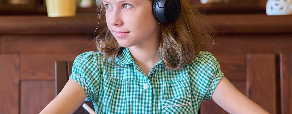 A schoolgirl working with headphones on her ears.